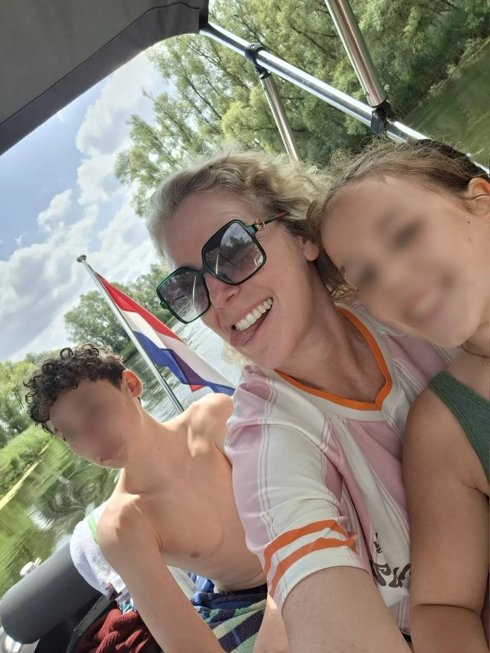 Jill met haar twee kinderen op een boot, de Nederlandse vlag achter hen
